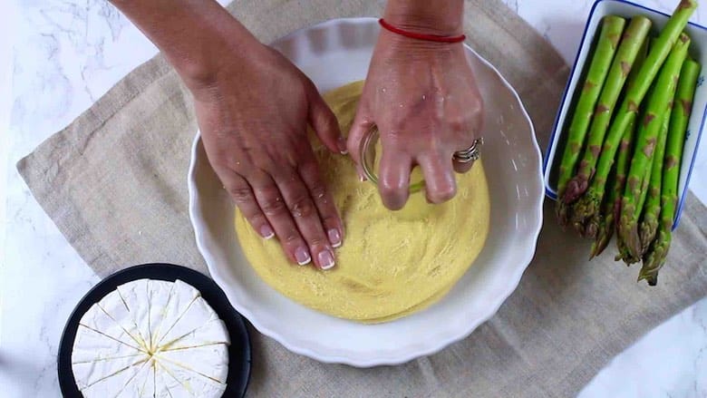 Easy Asparagus Keto Quiche spreading fathead dough onto a casserole