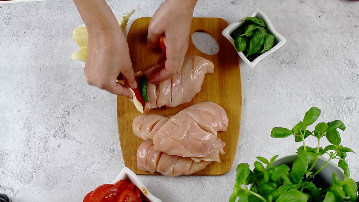 filling up hasselback chicken with mozzarella and basil