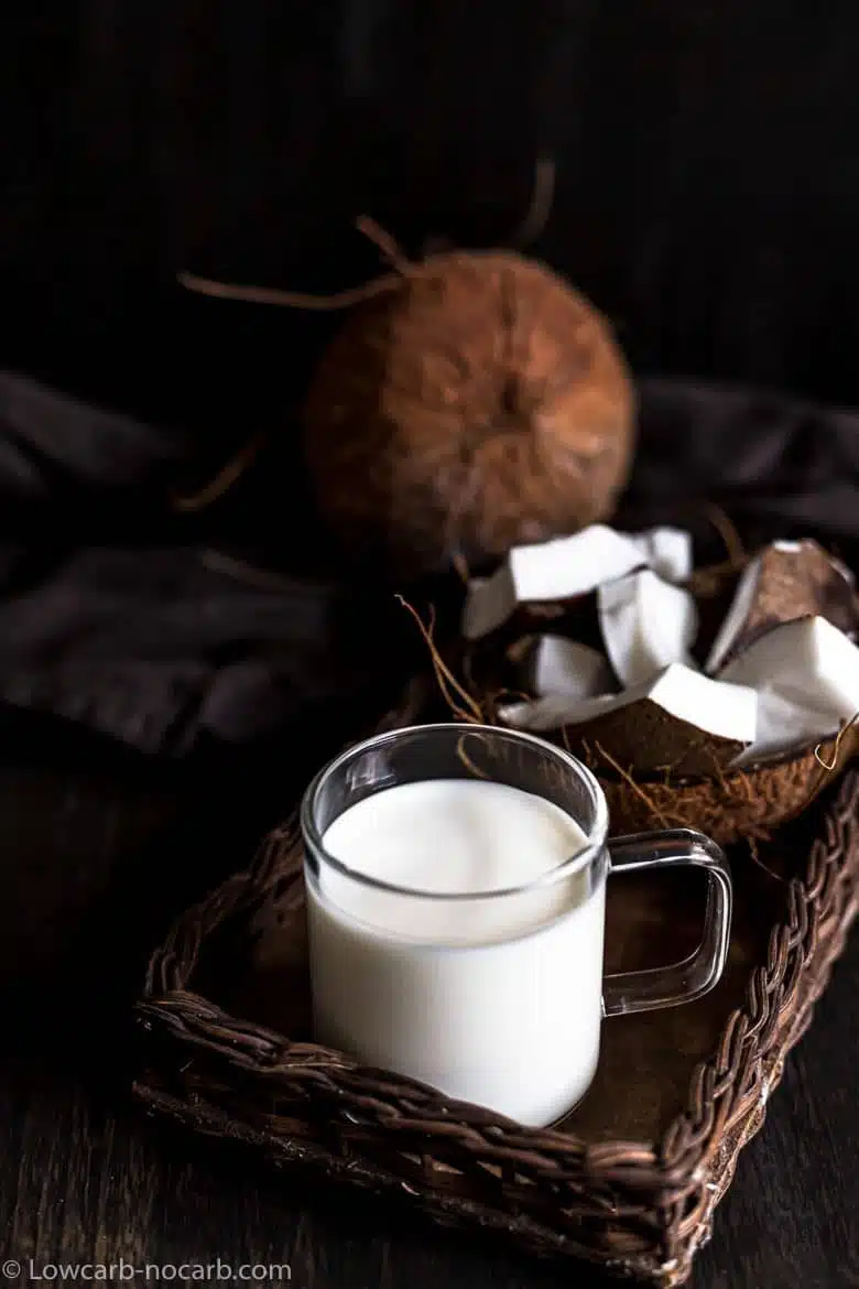coconut milk with whole coconut and pieces of coconut in the background