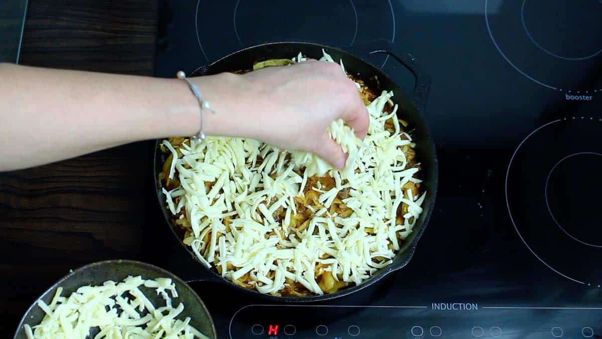 Cast Iron Keto Casserole spreading mozzarella cheese on top