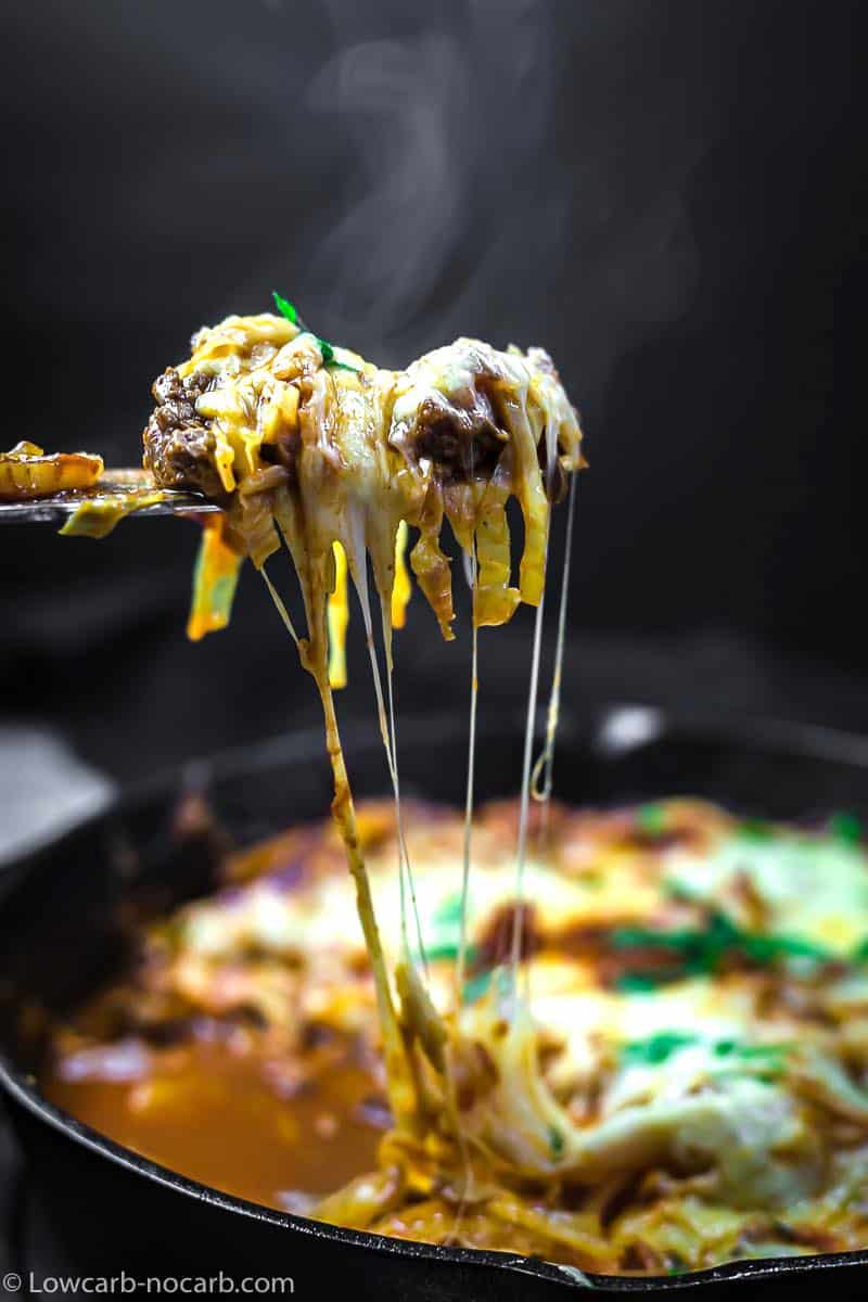 Keto Casserole with pulling the melted cheese from the skillet