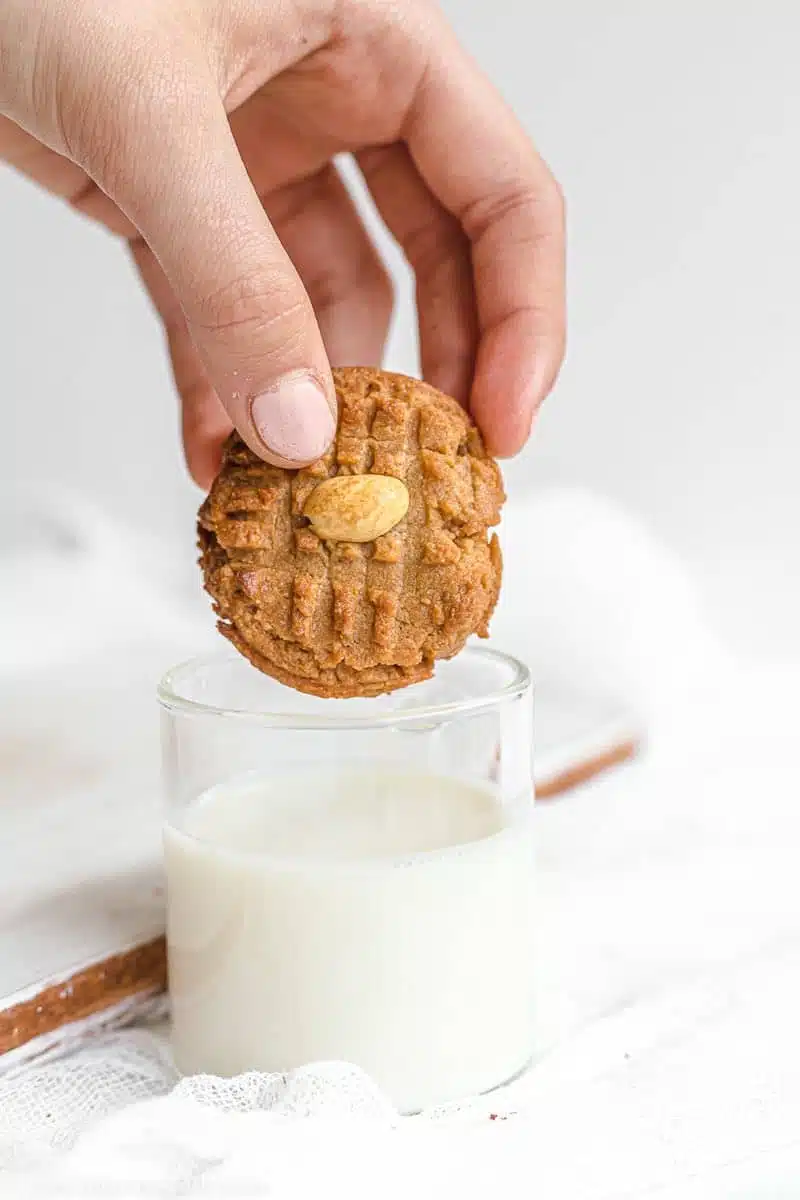 Keto Peanut Butter Cookie dipped in glass of nut milk