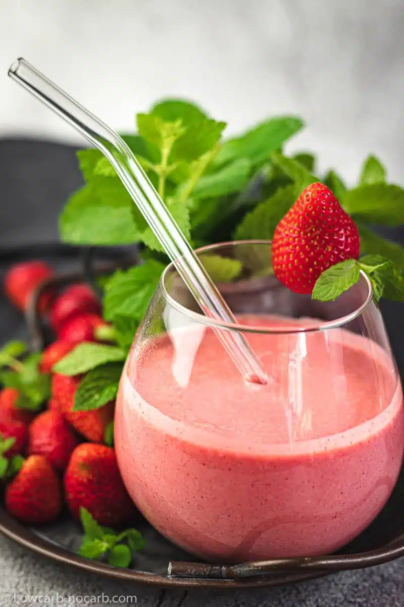 The Best Strawberry Keto Smoothie in a rustic tray with fresh strawberries and mint leaves