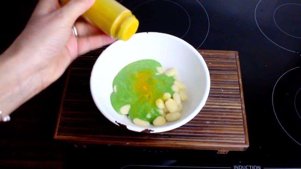 Spinach Keto Gnocchi being sprinkled with turmeric powder