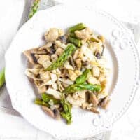 Chiken Noodles mixed with Tofu Shirataki Rice, mushrooms and asparagus on a white plate