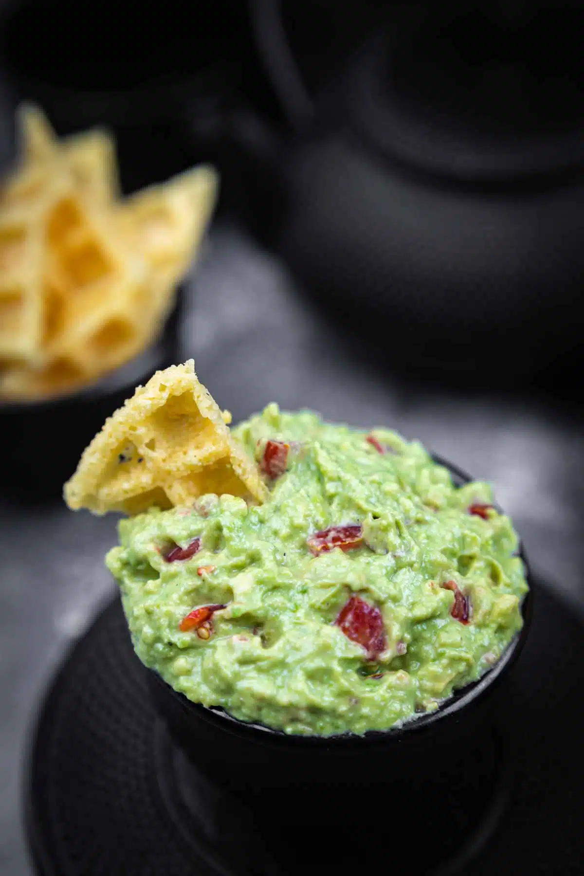 Super Simple Keto Guacamole in a black bowl with a chip dipped