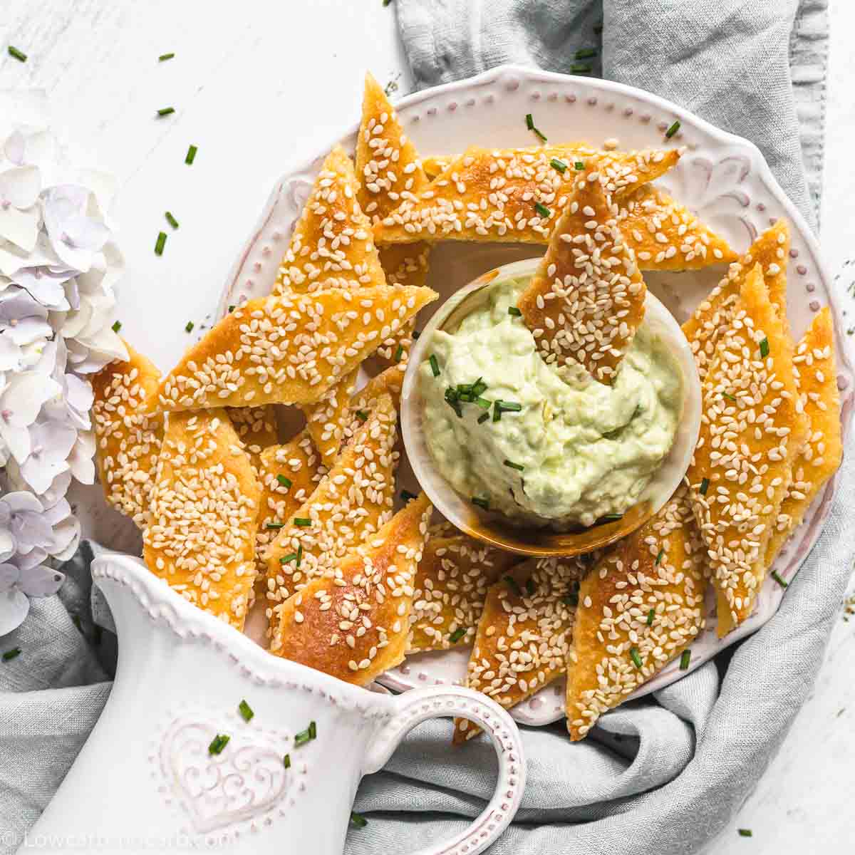 Sesame Crackers on a plate with jug and flower in a background