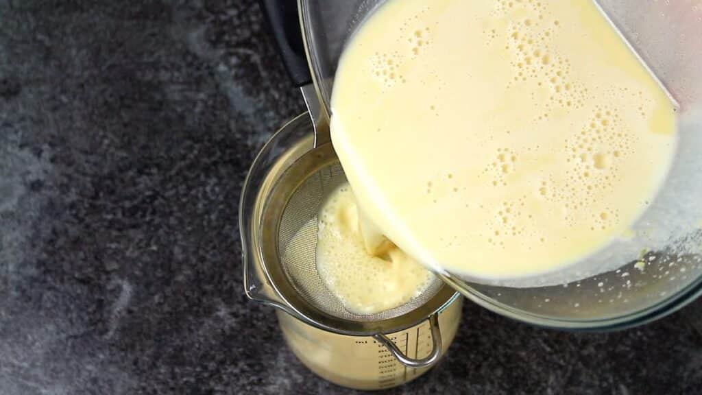Creamy Delicious Keto Eggnog pouring through sieve.