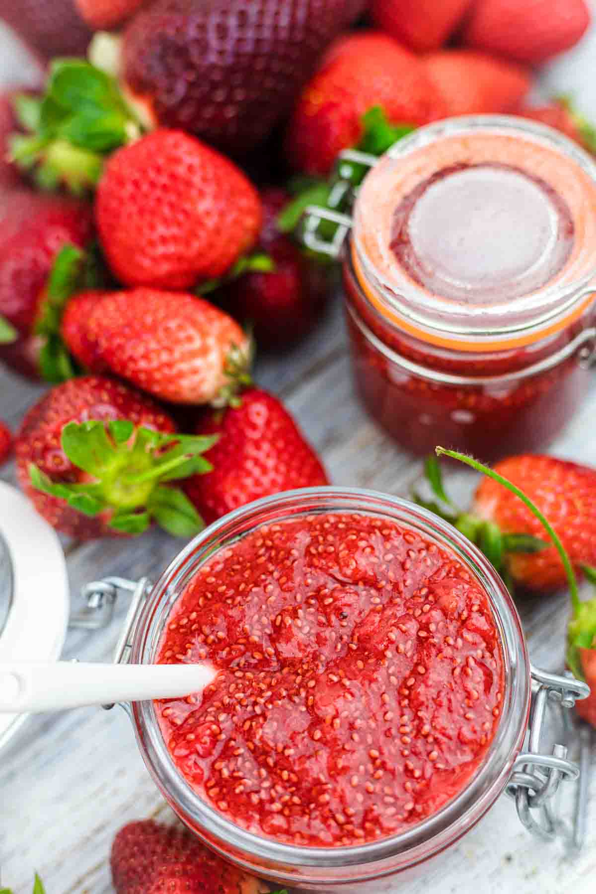 Low Sugar Strawberry Jam Recipe with spoon in a glass and fresh strawberries.