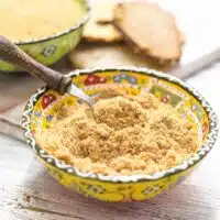 Keto Breadcrumbs in a yellow bowl with spoon.