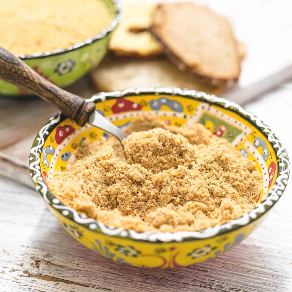 Keto Breadcrumbs in a yellow bowl with spoon.