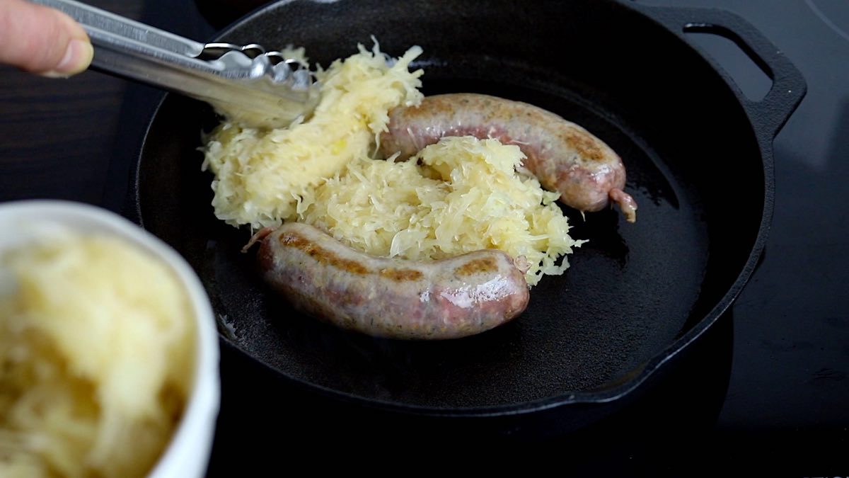 Baked Sausage in Oven adding sauerkraut to the pan.