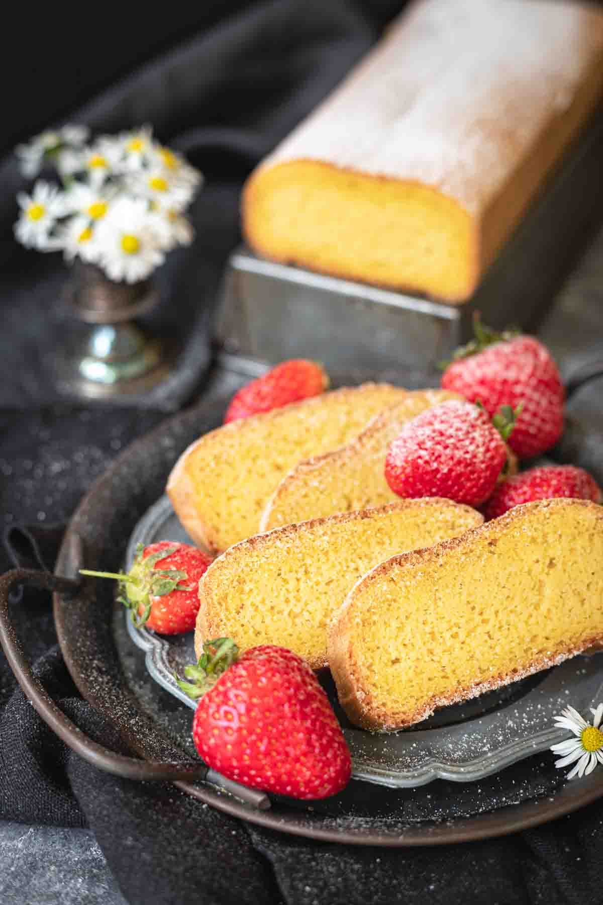 Almond flour pound cake on a plate cut into slices.