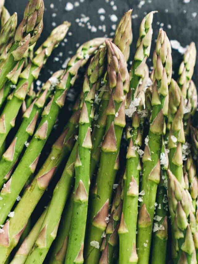 Fresh Asparagus with salt crystals on a dark wood.