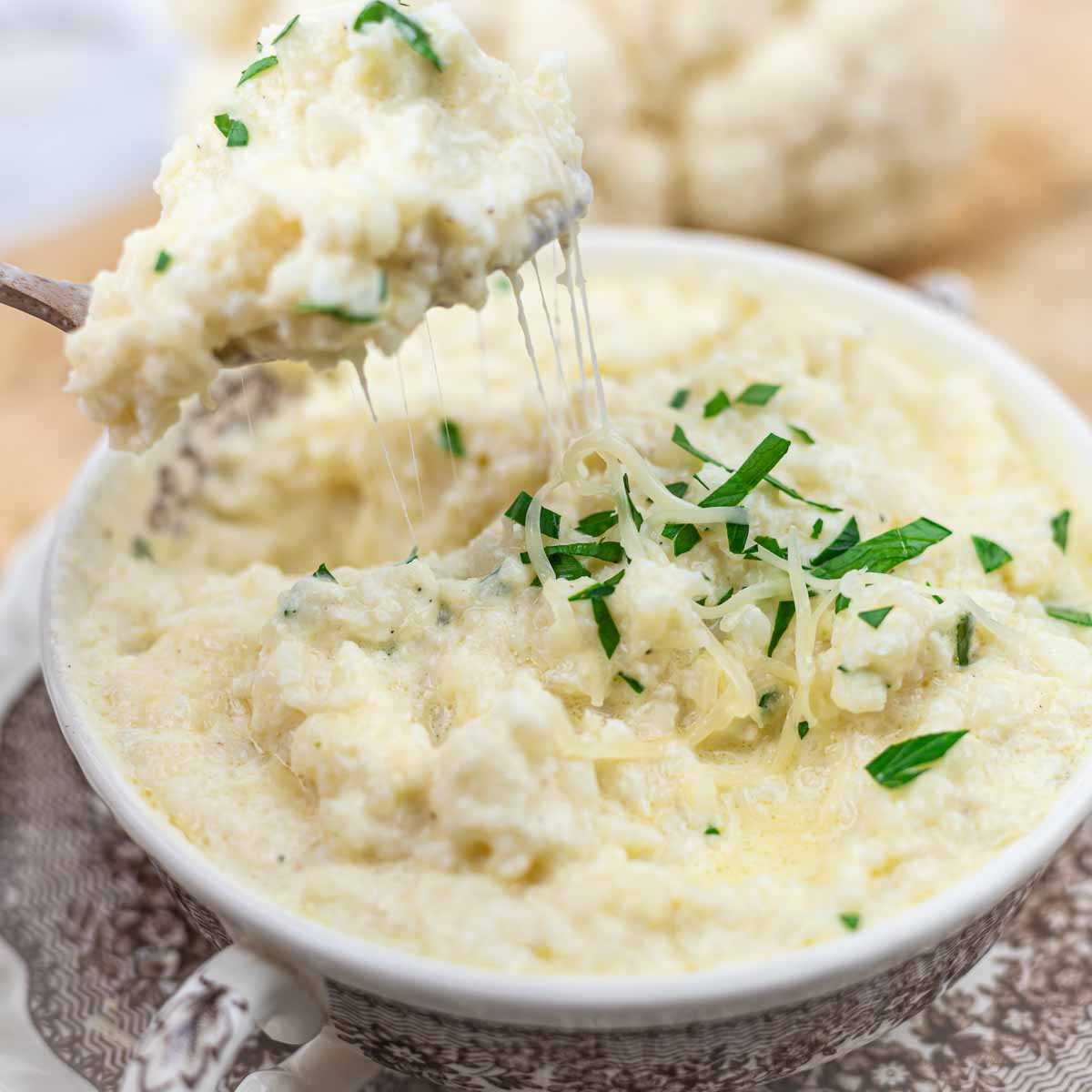 Riced cauliflower with cheese in a bowl with spoon out.