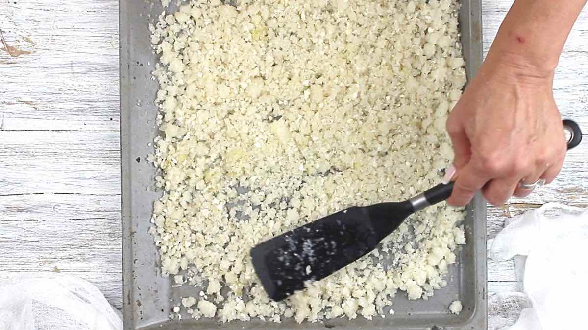Bake Frozen Cauliflower Rice spreading on a tray.