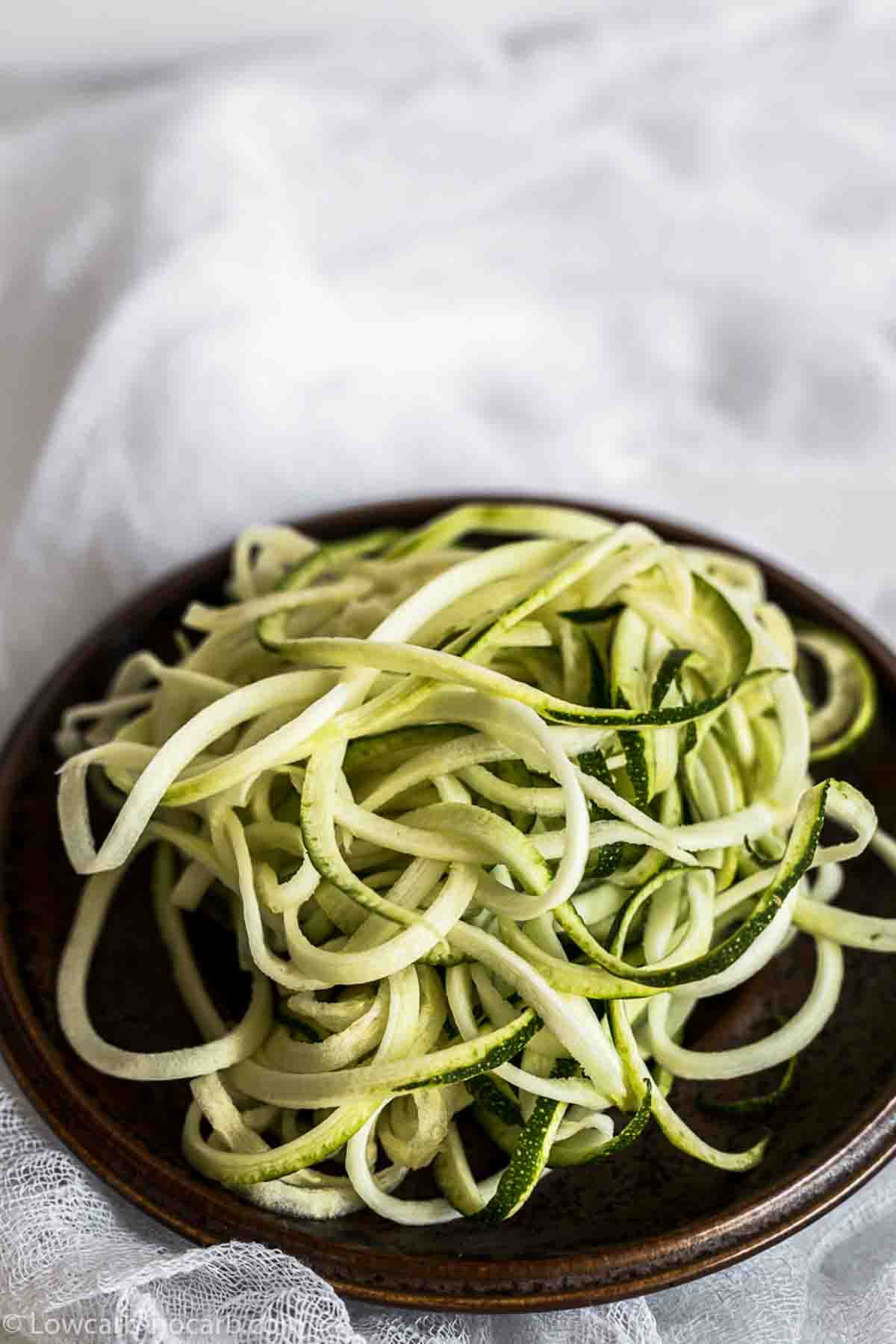 Zoodles on a brown plate.