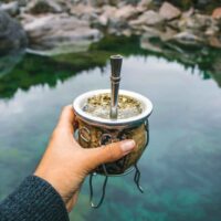 Holding Yerba tea cup over the lake.