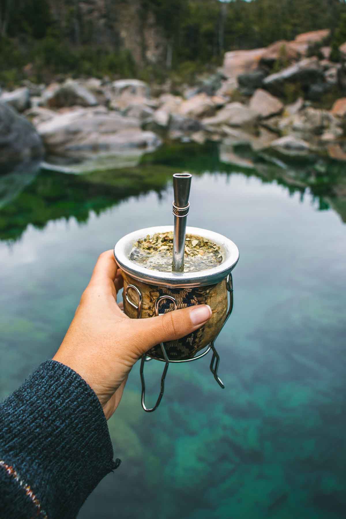 Holding Yerba tea cup over the lake.