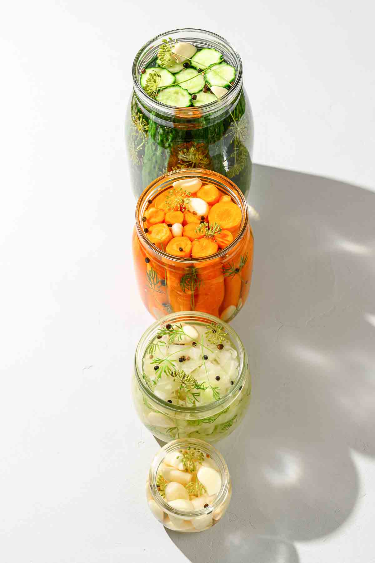 egetables cucumbers, carrots, cabbage and garlic in glass jars.