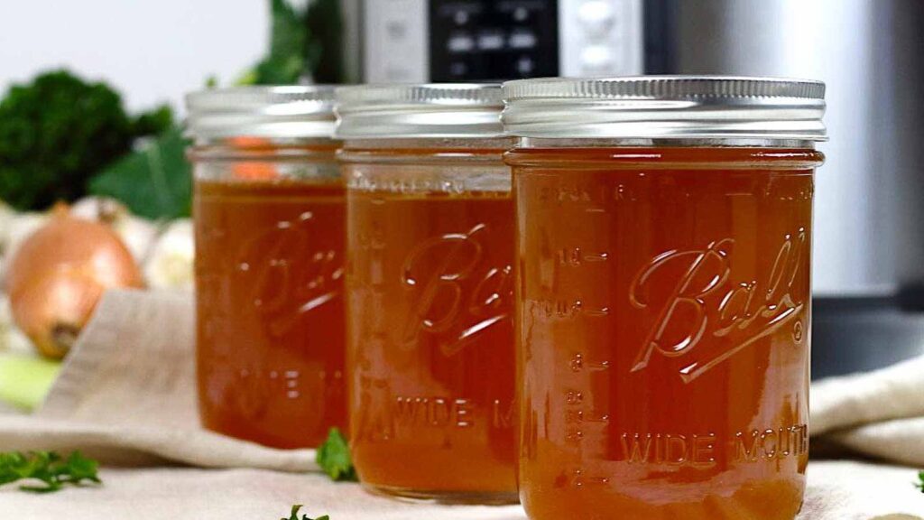 Three jars of broth in front of an instant pot.