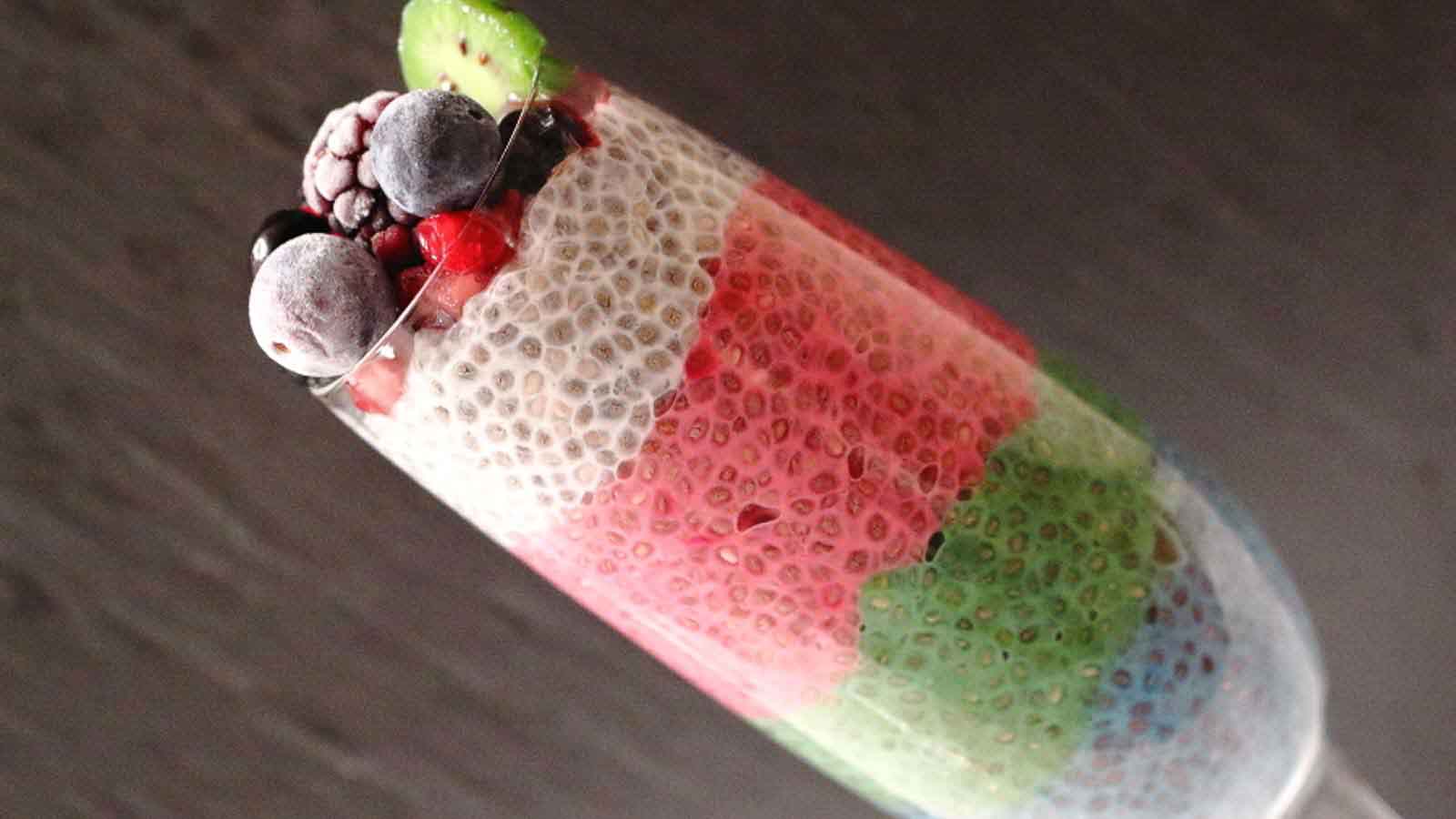 Rainbow Chia Pudding with dark background in a glass.