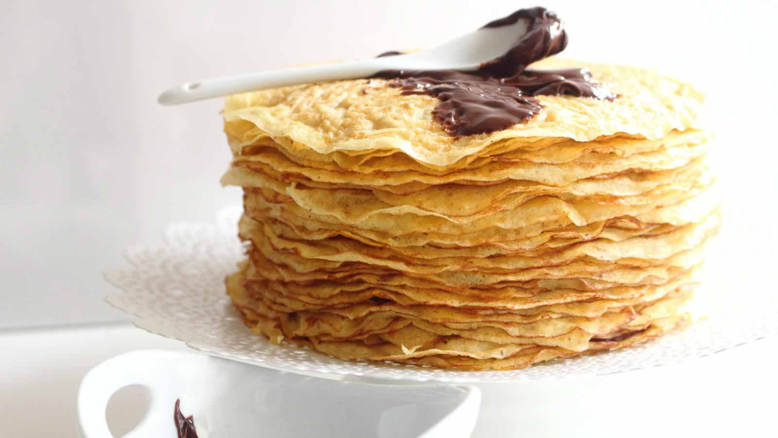 A stack of crepes with chocolate sauce on top.