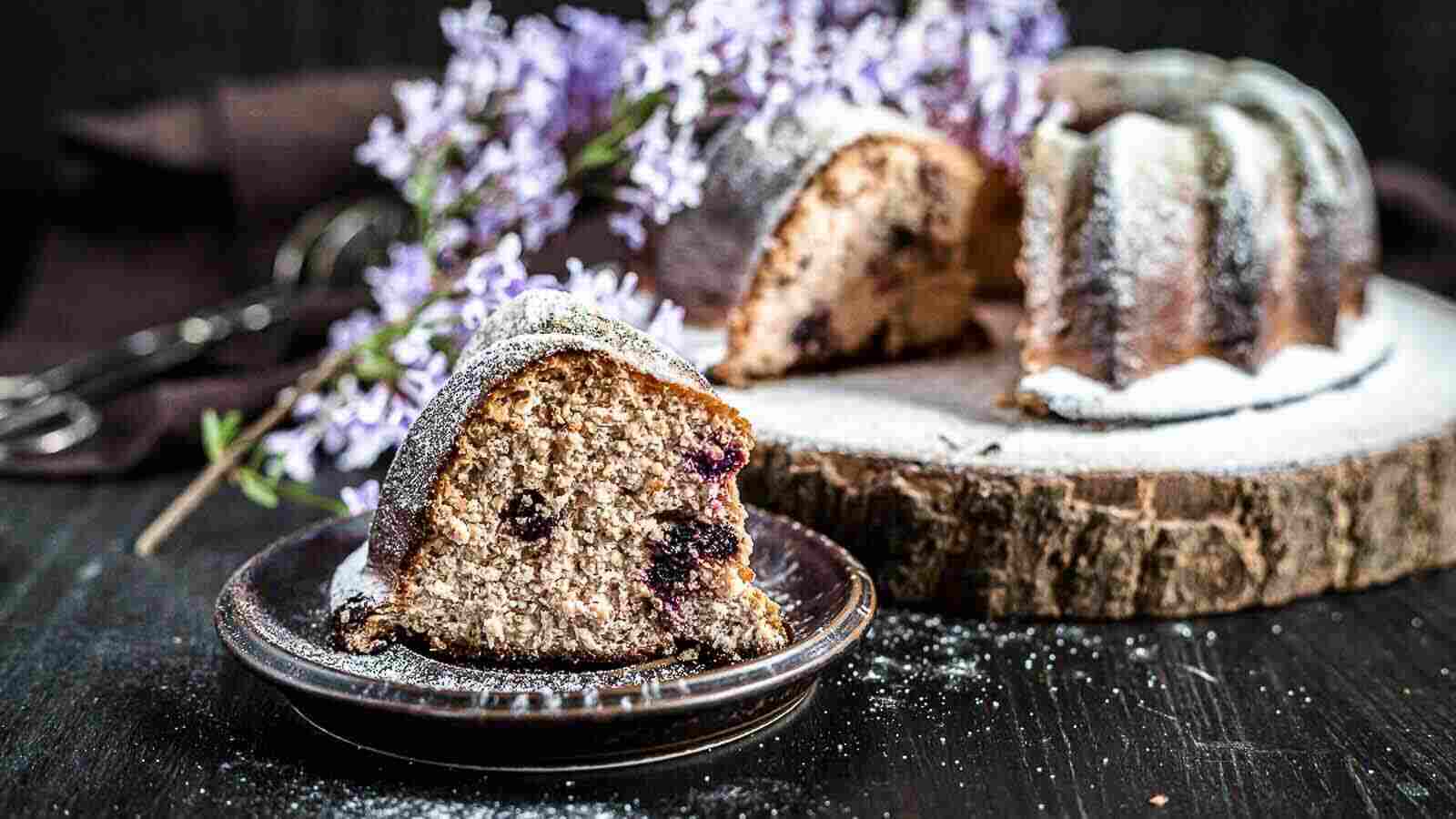 A bundt cake with blueberries on top of a wooden board.