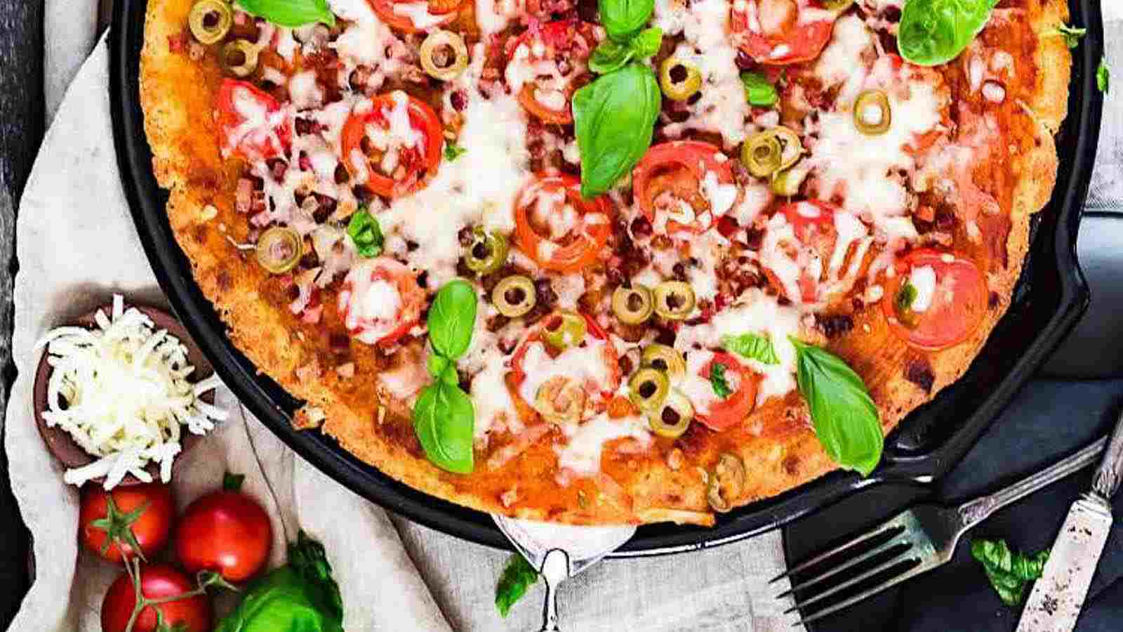 A pizza in a skillet with tomatoes and basil.