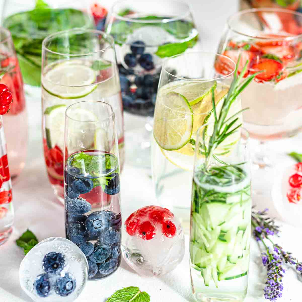 A table full of iced drinks with berries and mint.