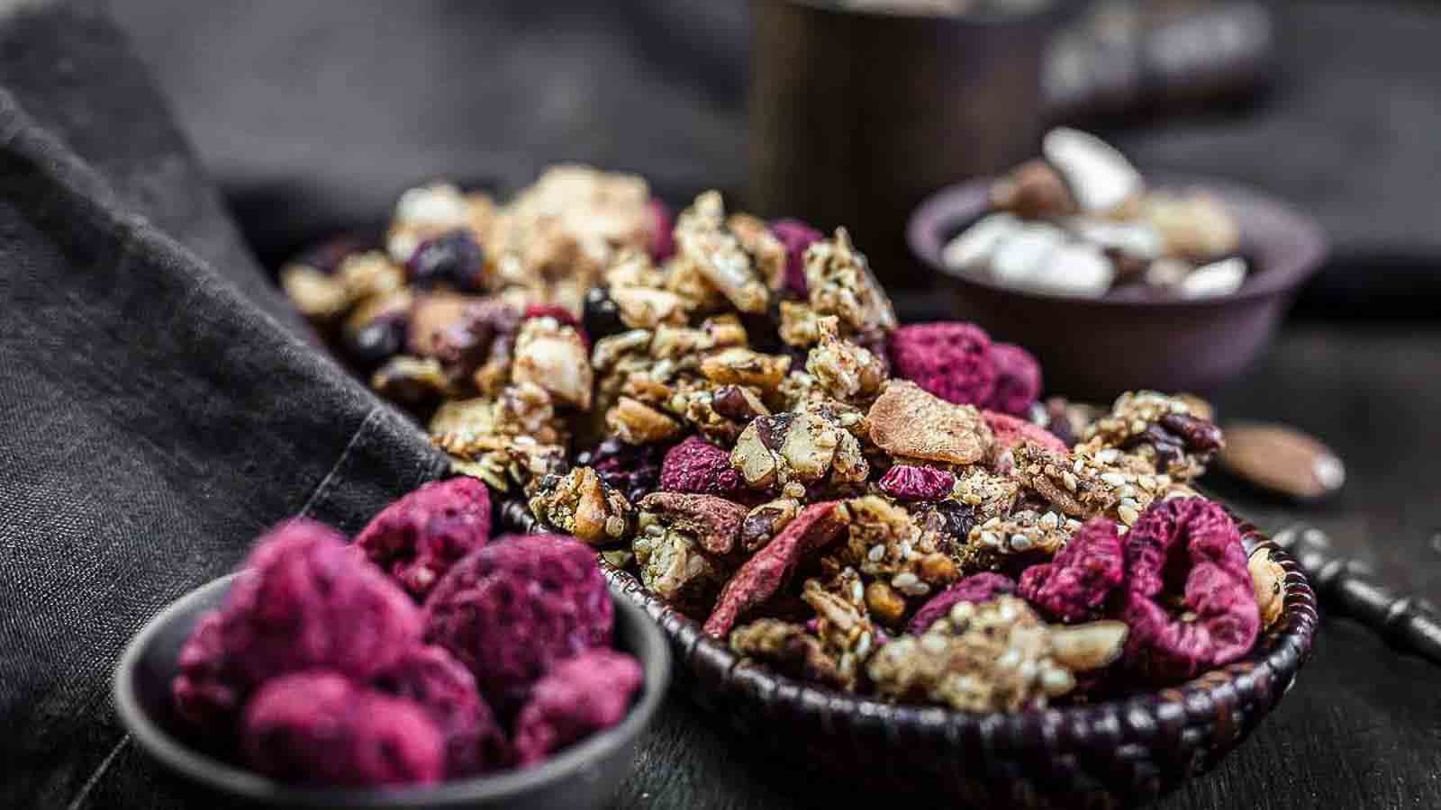 A bowl of granola with raspberries and nuts.