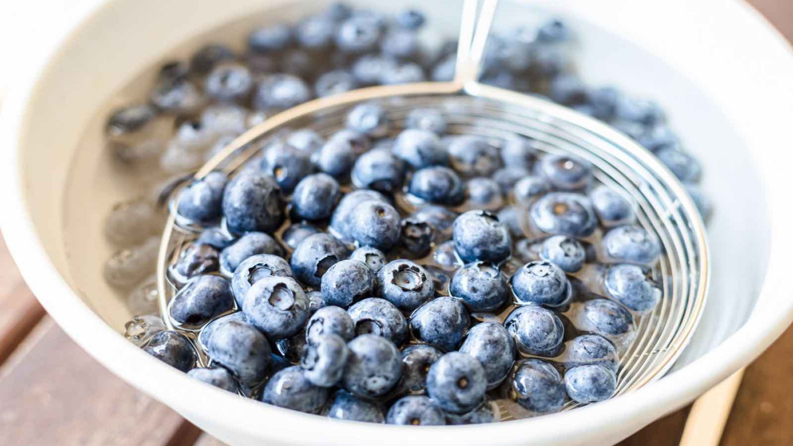 Blueberries in a white bowl on a wooden table.