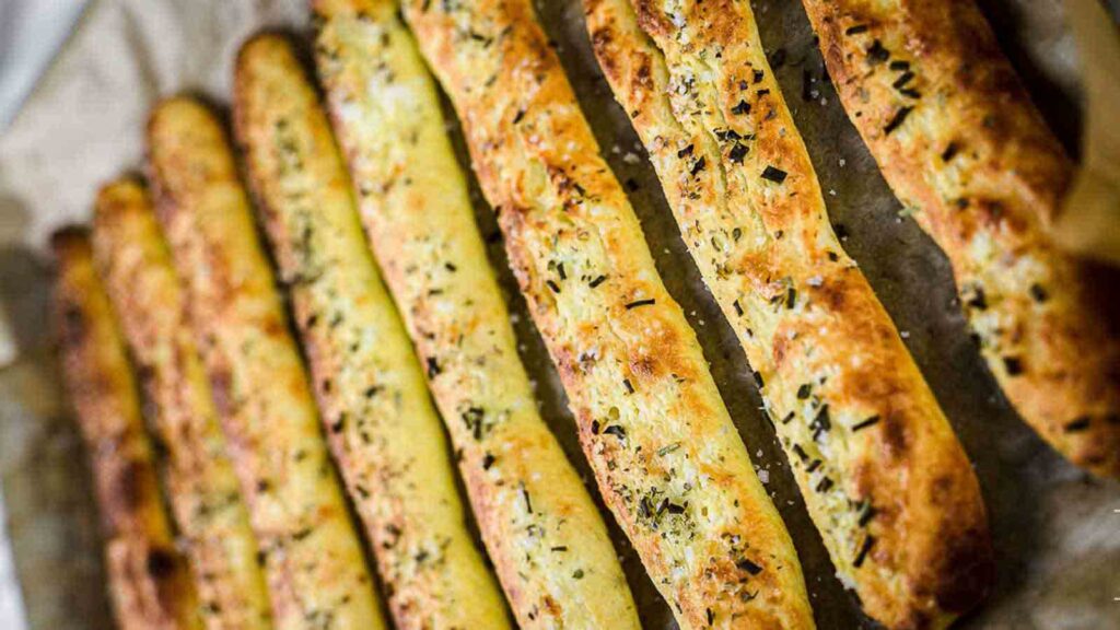 A tray of garlic bread sticks on a baking sheet.