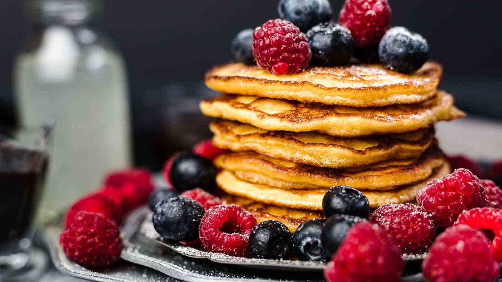 A stack of pancakes with blueberries and raspberries.