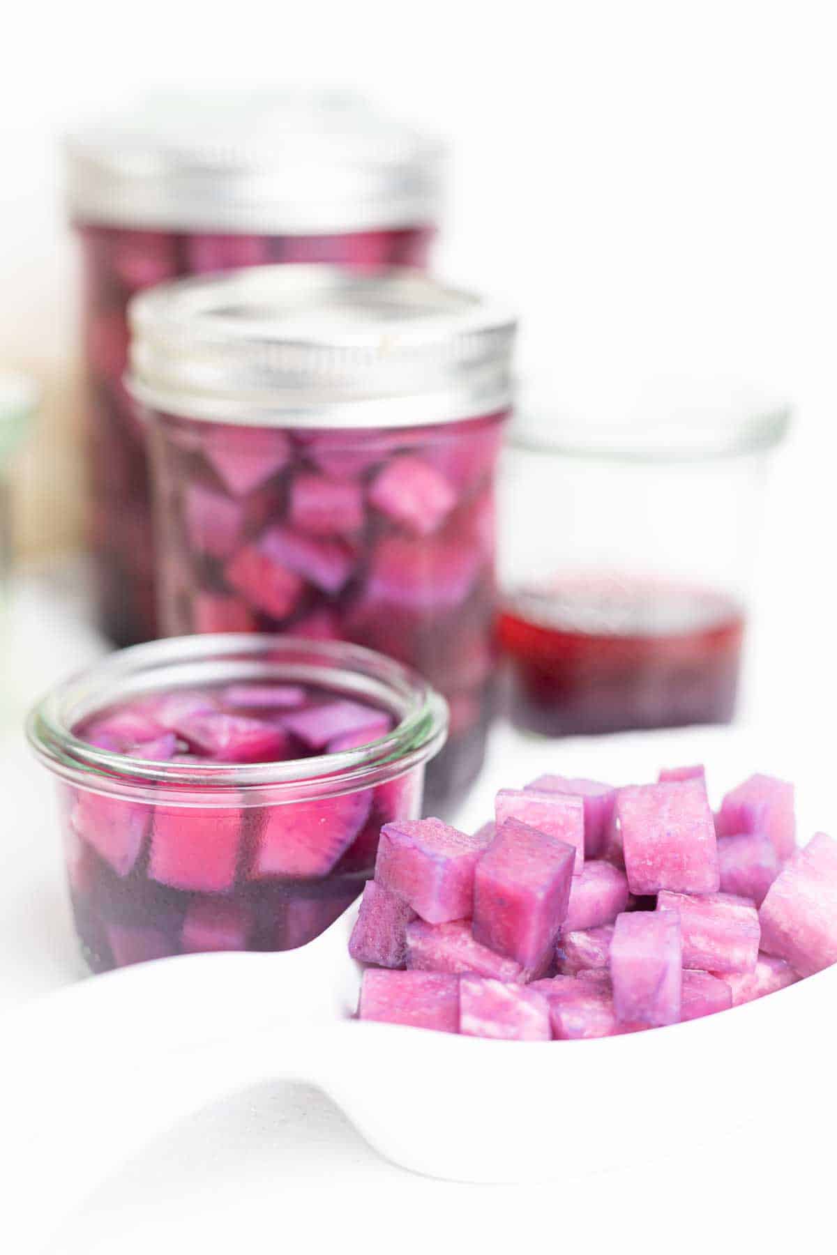 Jars of purple pickles on a white table.