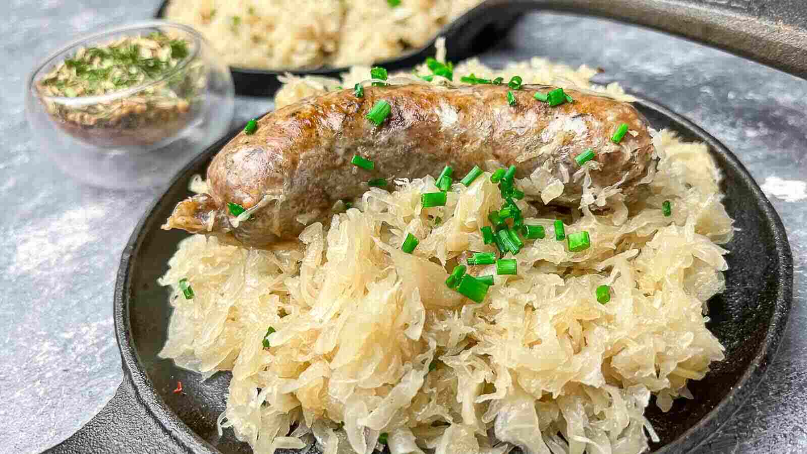 Baked Sausage and Sauerkraut on a cast iron plate.