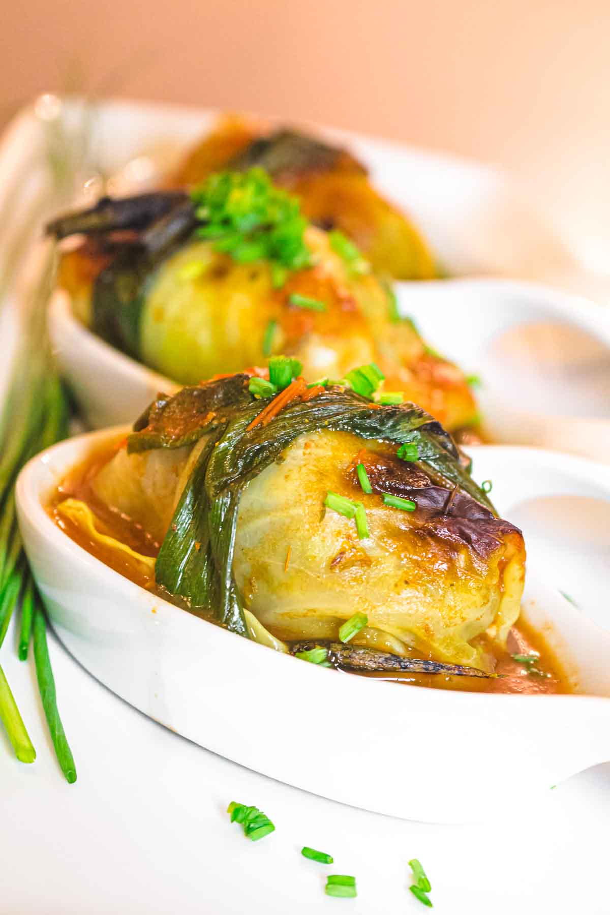 Stuffed cabbage with scallion and chives on a white plate.