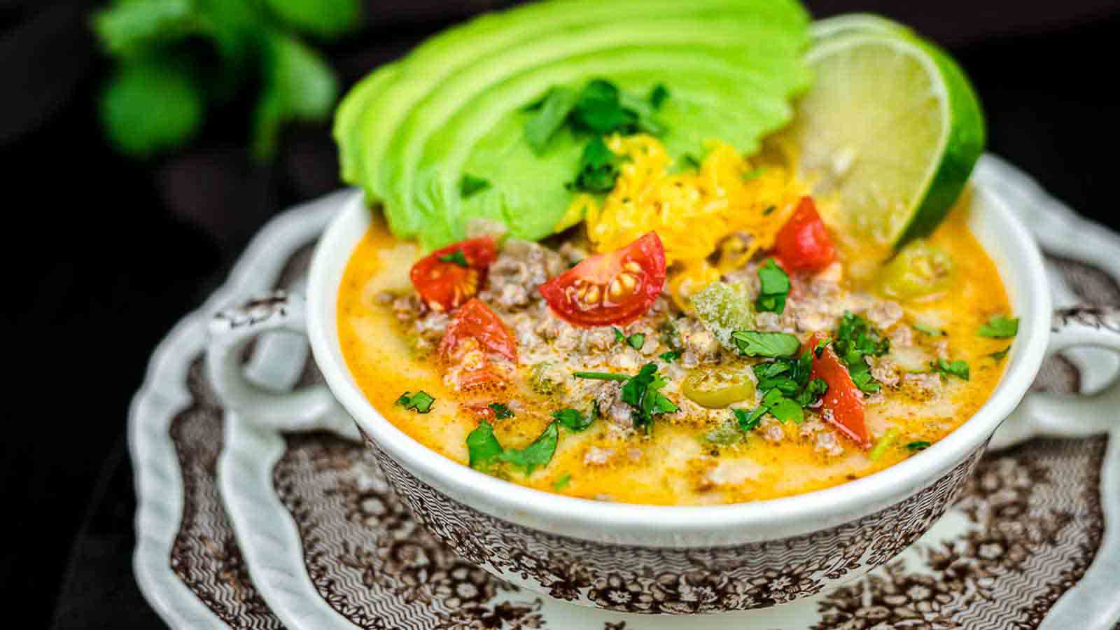 Taco soup with fresh avocado slices and lime.