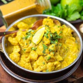 A bowl of chicken curry on a wooden table.
