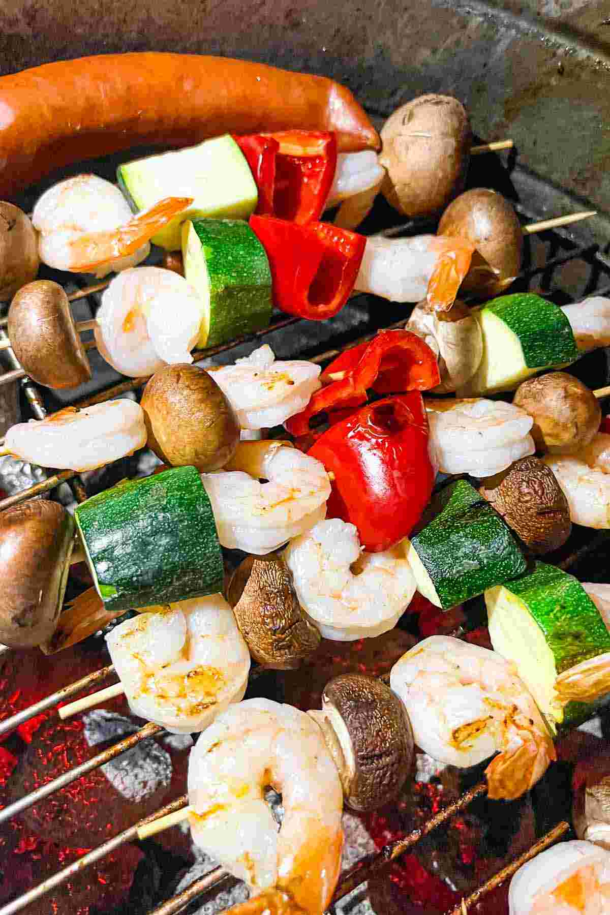 Shrimp and vegetables on skewers on a grill.