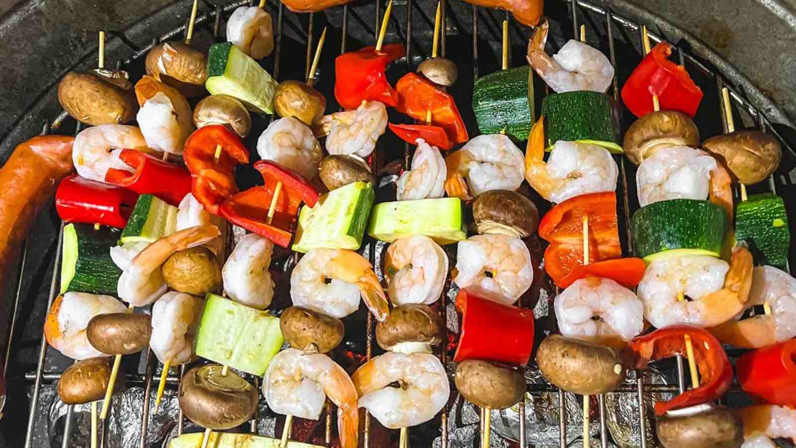 Skewers of vegetables and shrimp on a grill.