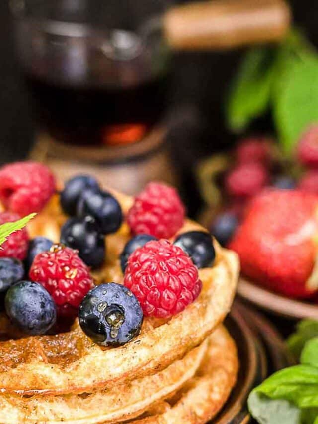 A stack of waffles with berries and mint.