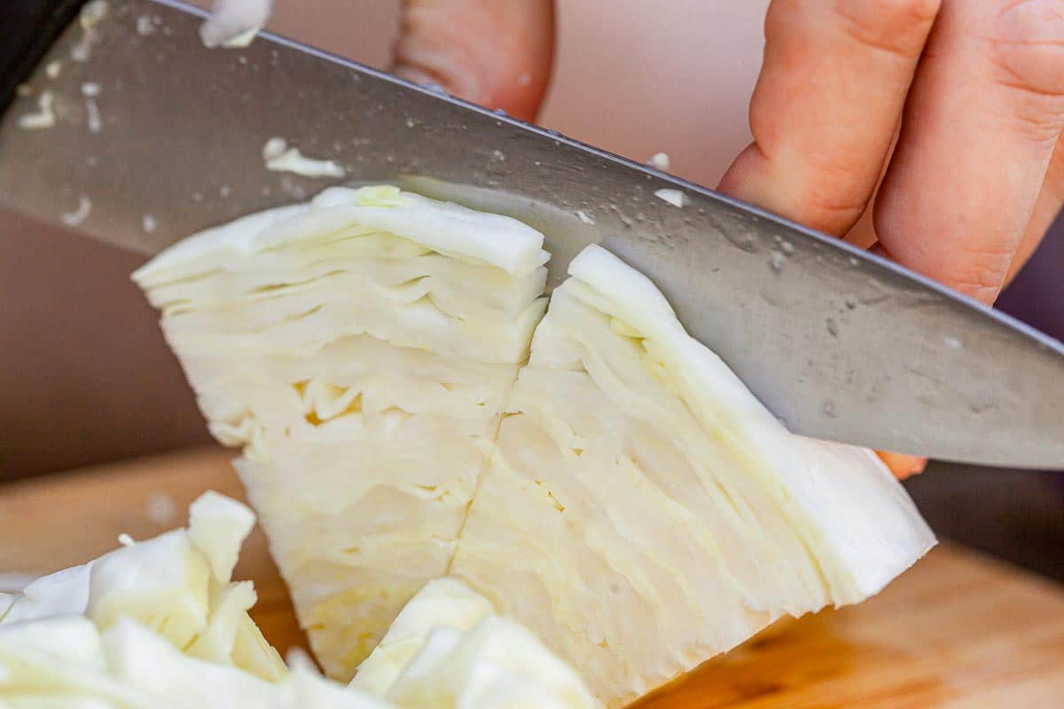 A person is slicing a piece of cabbage.