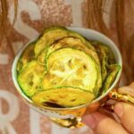 A person holding a bowl of zucchini chips.