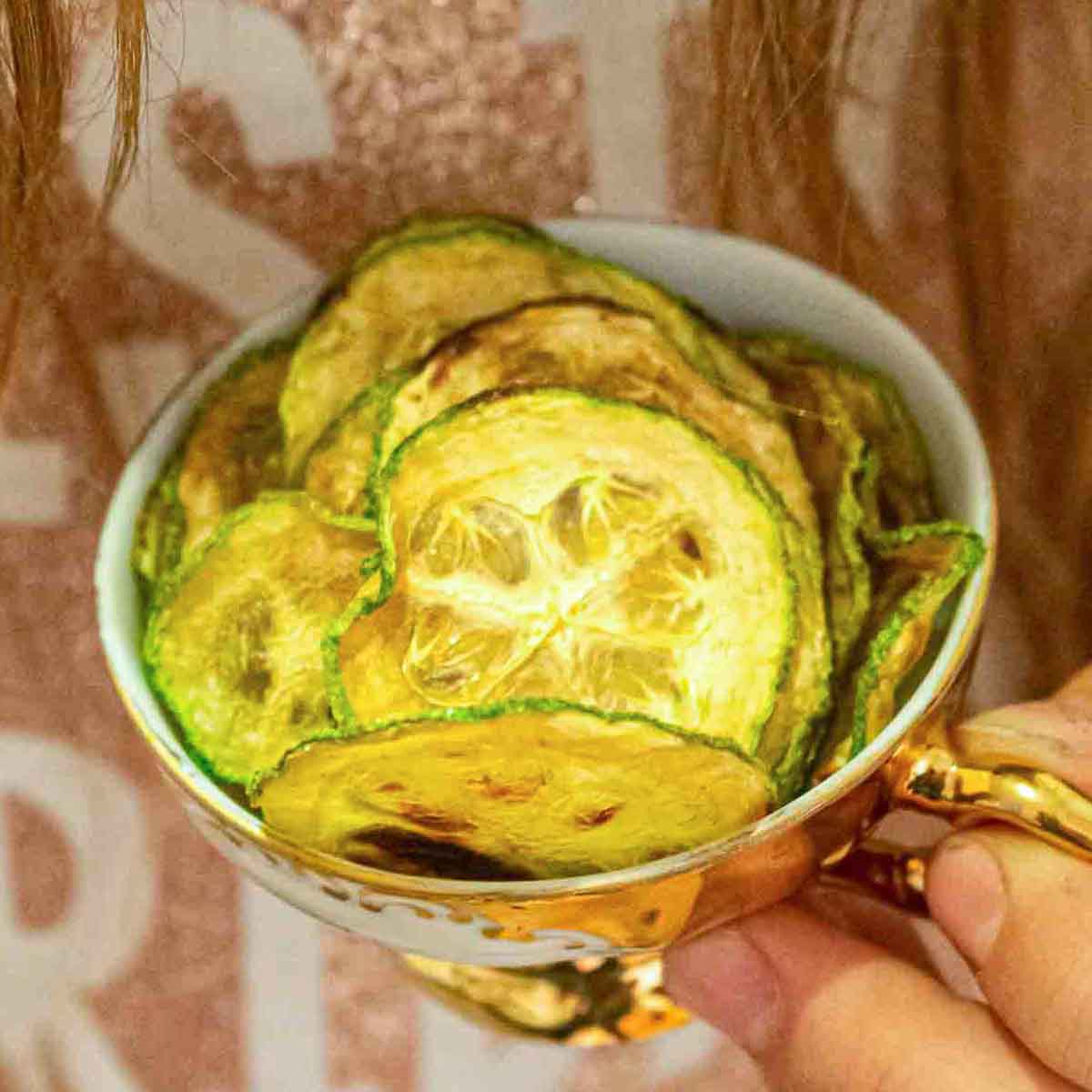 A person holding a bowl of zucchini chips.