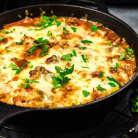 A skillet full of meat and cheese on a table.