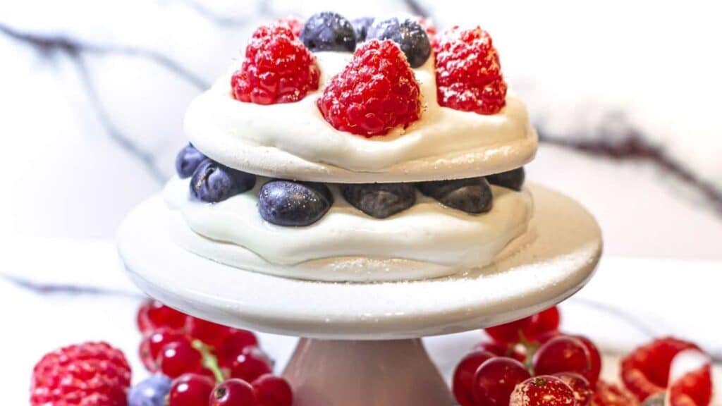 Pavlova topped with berries and whipped cream.
