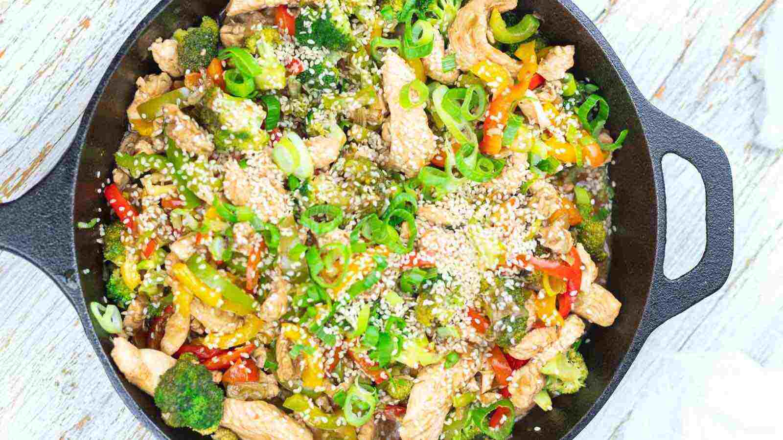 A skillet with vegetables and chicken in it.