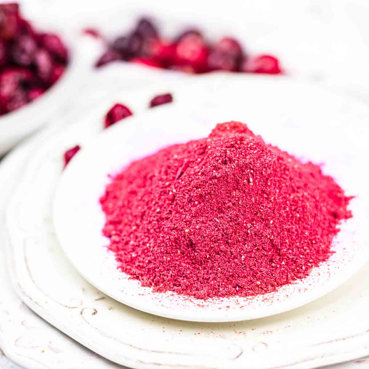 Cranberry powder on a plate next to cranberries.