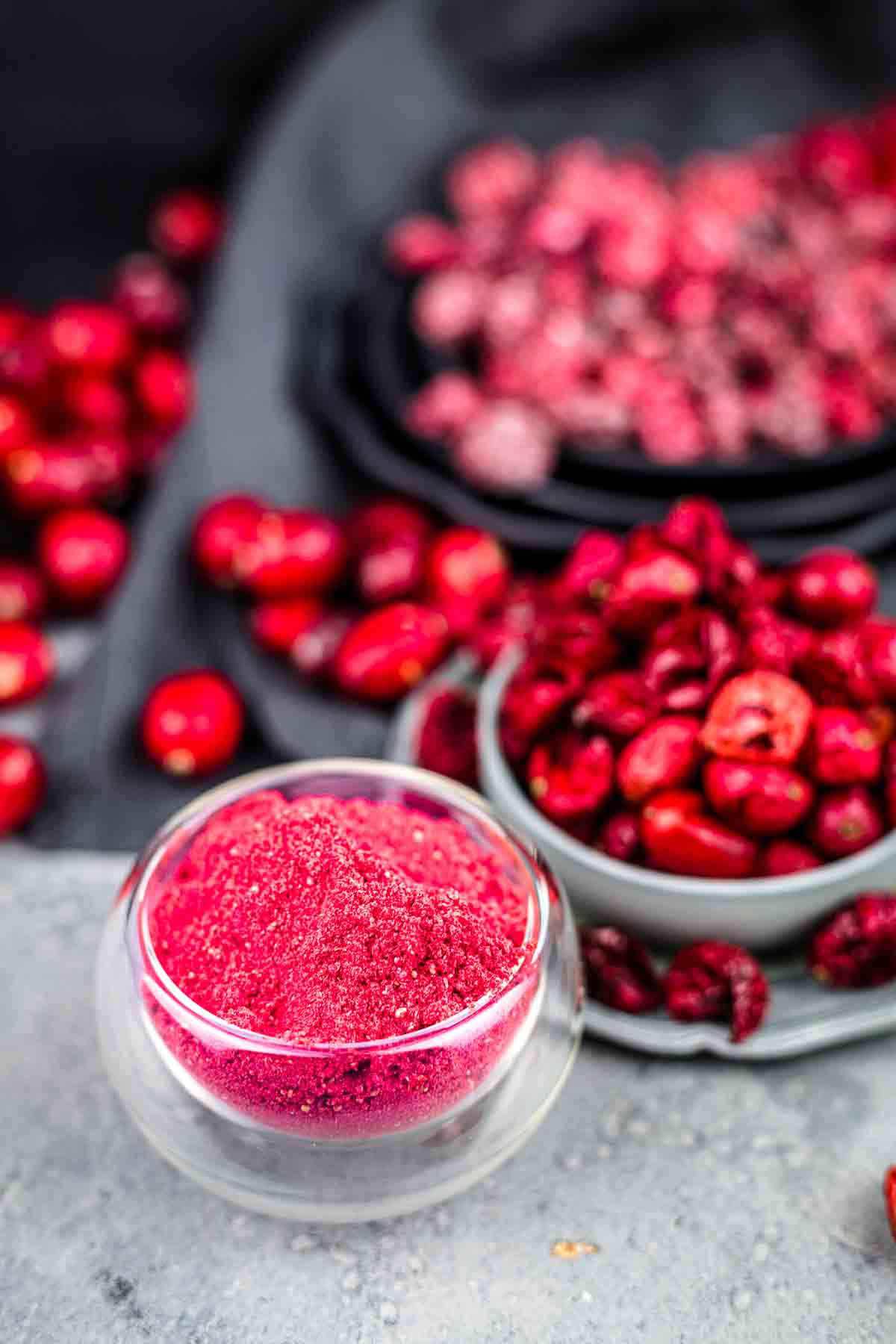 Cranberry powder in a bowl next to red berries.